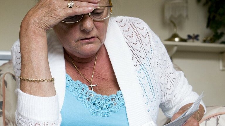 Demanding help for pensioners Woman looking concerned while reading a piece of paper